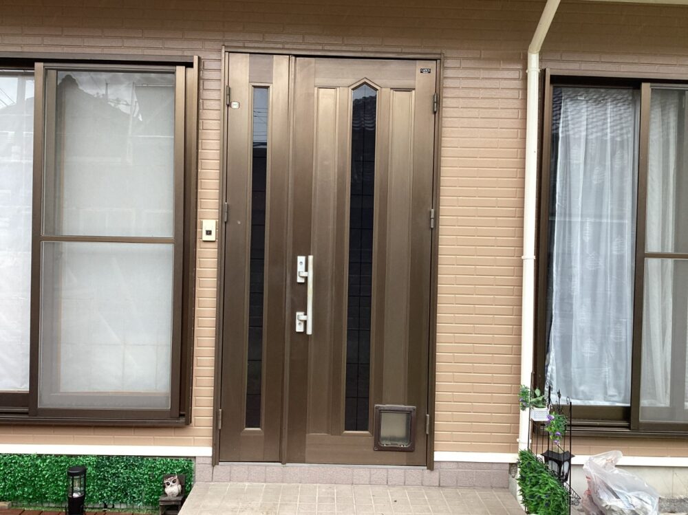 施工前：シンプルで落ち着いたデザインの玄関扉。年月を感じさせる風合いがありました。